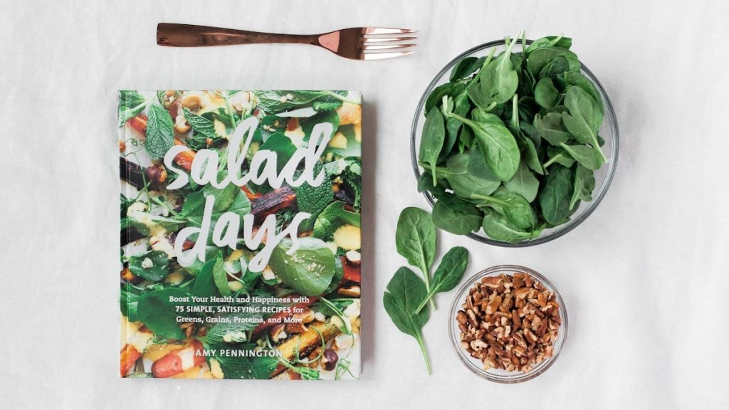 Salad day cookbook beside clear glass bowl with vegetable