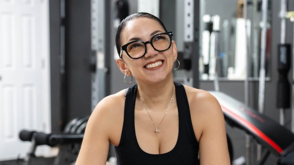 Woman smiles happily in her home gym.