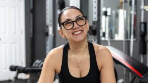 Woman smiles happily in her home gym.
